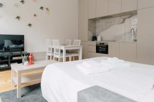ein weißes Schlafzimmer mit einem weißen Bett und einer Küche in der Unterkunft Casa Burguesa Rua do Almada - Porto city center in Porto