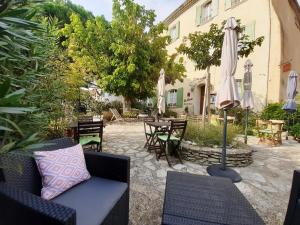 um pátio exterior com um sofá e um guarda-chuva em Hôtel Le Siècle em Mazan