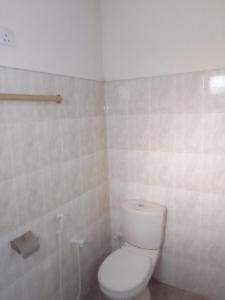 a bathroom with a toilet and a tiled wall at New Green Garden Hotel & Safari in Tissamaharama
