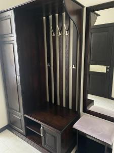 a dark wooden cabinet with a bench in a room at Sun Lidia in Chernivtsi
