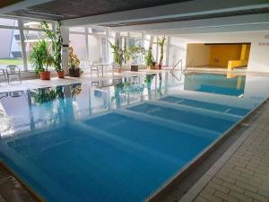 a large swimming pool with blue water in a building at Ferienwohnung Winklworld inklusive aktivCARD in Sankt Englmar