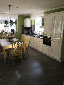 a kitchen with white cabinets and a table with chairs at Unterkunft am See in Skånes Fagerhult