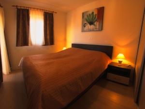 ein Schlafzimmer mit einem Bett und einer Lampe auf einem Tisch in der Unterkunft Apartment Omanović in Čižići