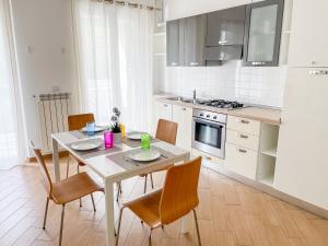 una cocina con mesa y sillas y una cocina con electrodomésticos blancos. en Homiday - Residence K2, en Pineto