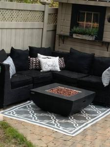 a black couch and a fire pit on a patio at Relaxing modern home with In-ground pool in Burlington