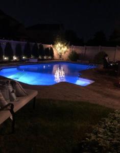 a swimming pool at night with blue illumination at Relaxing modern home with In-ground pool in Burlington
