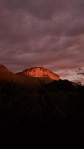 Ein Berg, auf dem die Sonne bei Sonnenuntergang scheint in der Unterkunft Pousada Canto das Cachoeiras in Vale do Capao