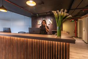 a woman talking on a cell phone at a reception desk at Bon 17 Hotel By SHG in Bogotá