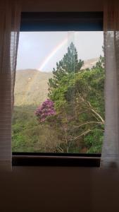 einen Blick auf einen Regenbogen aus einem Fenster mit einem Baum in der Unterkunft Pousada Canto das Cachoeiras in Vale do Capao