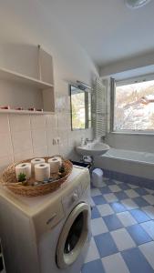 ein Badezimmer mit einer Waschmaschine und einem Waschbecken in der Unterkunft Al Bel VEDER in Levico Terme