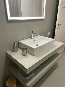 - un lavabo blanc dans la salle de bains sous un miroir dans l'établissement Number 99 - Number House, à Bergame