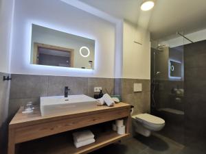 een badkamer met een wastafel, een toilet en een spiegel bij Sieghards Home in Mayrhofen