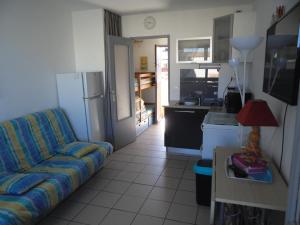 Una sala de estar con un sofá y una cocina. en ARCHE DE NOE 1, en Cap d'Agde