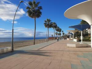 een stoep op het strand met palmbomen en de oceaan bij Apartamento en casco histórico in Estepona