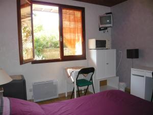 a bedroom with a bed and a table and a window at MARC in Saint-Paul-Trois-Châteaux