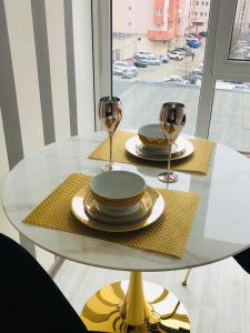 a white table with plates and wine glasses on it at Garsoniera centru pietonal in Târgu Jiu