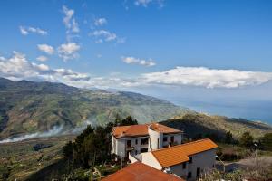 uma casa numa colina com montanhas ao fundo em Paese Albergo - Arconides em Motta D'affermo