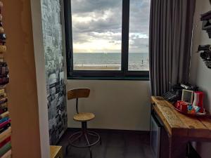 Zimmer mit einem Schreibtisch und einem Fenster mit Blick auf den Strand. in der Unterkunft Hotel Perla in Riccione