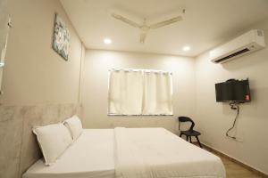 um quarto com uma cama branca e uma televisão em HOTEL TRP BLISS em Nizāmābād