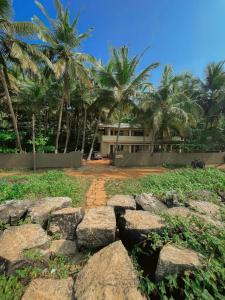a house with palm trees and rocks in front of it at Kizhunna rock beach house in Kannur