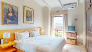 a bedroom with a white bed and a television at San Lameer 3123 by Top Destinations Rentals in Southbroom