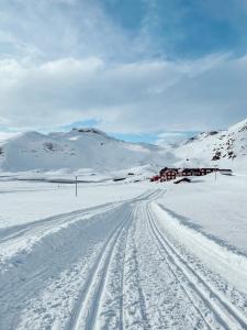 a snow covered road with a house in the distance at Bygdin Høyfjellshotell in Beitostøl