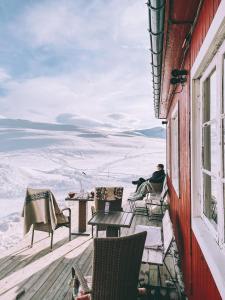 un hombre sentado en un balcón con vistas a las montañas cubiertas de nieve en Bygdin Høyfjellshotell, en Beitostølen