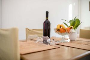einen Tisch mit einer Flasche Wein und einer Schale Obst in der Unterkunft Apartmani Luka in Rab