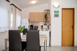 une cuisine avec une table et deux chaises et une cuisine avec une cuisine dans l'établissement Apartmani Luka, à Rab