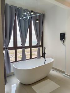 Bali Residences Homestay Melaka Town في ميلاكا: حوض استحمام أبيض في حمام مع نافذة
