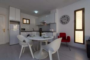 een keuken met een tafel en stoelen en een klok aan de muur bij Mare Verde 1 in Adeje