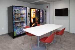 a white table and red chairs in front of a refrigerator at Motel 6 Highland CA San Bernardino East in Highland