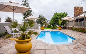 a swimming pool in a yard with an umbrella at Avanti Guest Lodge in Vredenburg