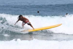 un hombre montando una ola en una tabla de surf en el océano en Chris Guest House, en Rincón