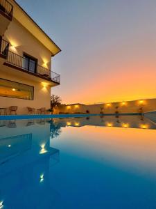 une villa avec une piscine au coucher du soleil dans l'établissement Amada Hotel Siracusa, à Syracuse
