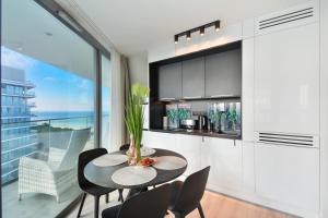 a dining room with a table and chairs and a large window at Apartamenty Sea Towers SeaView by Rent like home in Międzyzdroje