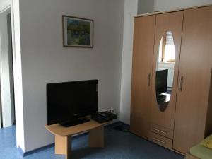 Habitación con escritorio, TV y armario. en Kleine Ferienwohnung en Vöhringen