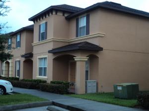 a brown house with a car parked in front of it at Four Bedroom Townhouse in Regal Oaks at Old Town in Orlando