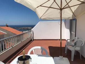 einen Balkon mit einem Sonnenschirm, einem Tisch und Stühlen in der Unterkunft A Terraza da Filipa in Vila Praia de Âncora