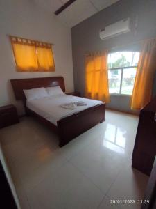 1 dormitorio con 1 cama grande y cortinas amarillas en HOSTERIA PUERTO BALBANERA, en Tonsupa