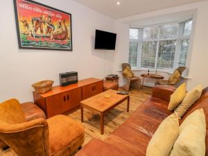 a living room with a couch and chairs and a tv at Bronwen House in Llanbedr