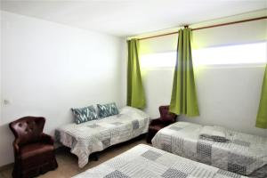 ロザスにあるGlobal Immo 2035 Olympiaのベッドルーム1室(ベッド2台付)、緑のカーテン付きの窓が備わります。
