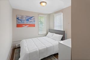 a white bedroom with a white bed and a painting at 5BR Beach Block Orange Loop Steps from Boardwalk in Atlantic City