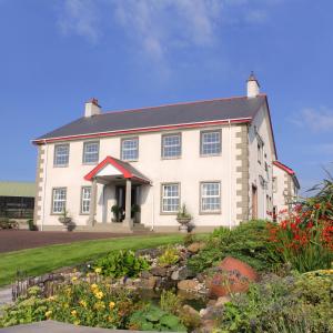 a large white house with a garden in front of it at Carnalbanagh House in Portstewart