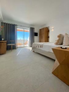 a bedroom with a bed and a view of the ocean at Calistus Mykonos in Mikonos