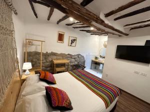 Un dormitorio con una cama con un televisor en la pared. en CASA CRISTOBAL Siete Cuartones, en Cusco
