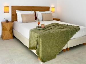 a bedroom with a large white bed with a green blanket at Calistus Mykonos in Mikonos