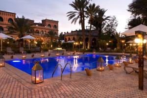 una piscina con luci di fronte a un edificio di OZ Palace Ouarzazate & SPA a Ouarzazate