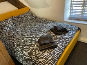 a bed with two towels on top of it at Blackbird Cottage in Kettering