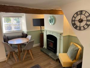 a living room with a table and a fireplace at Blackbird Cottage in Kettering